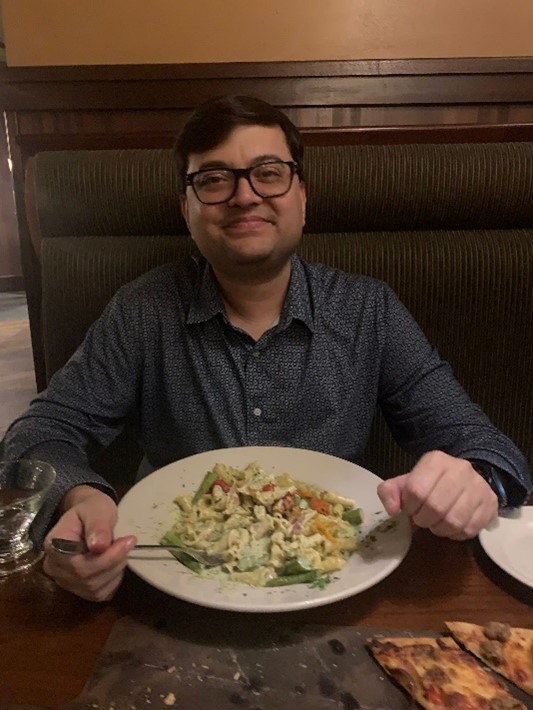 A person sitting at a table with a plate of food  Description automatically generated